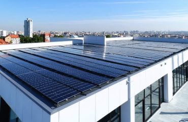 Aerial view of a commercial building equipped with solar panels and protective weather and security systems, representing the investment in sustainable energy and environmental leadership.