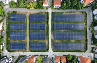 Aerial view of a community solar garden with solar panels integrated into a neighborhood, showcasing diverse households and illustrating accessible clean energy for every home.