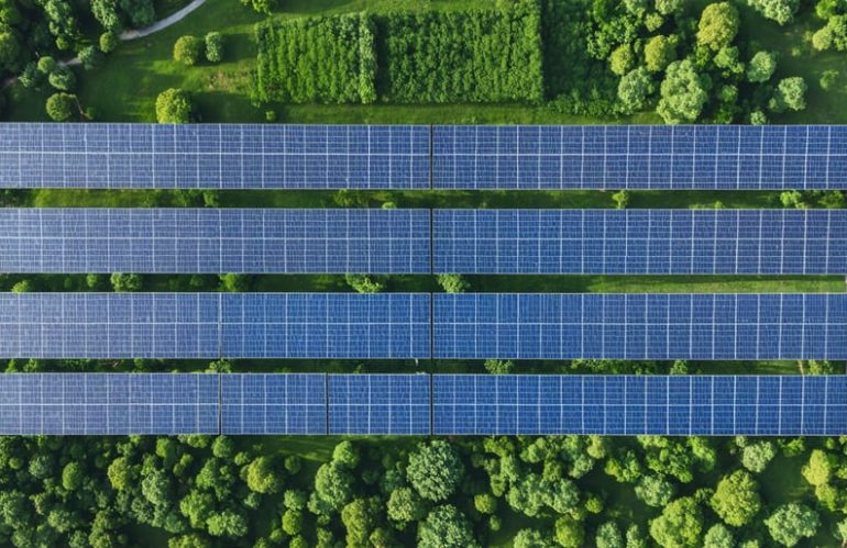 Aerial illustration displaying a solar farm with landscaped green buffer zones, illustrating the integration of solar panels within a residential area for sustainable development.